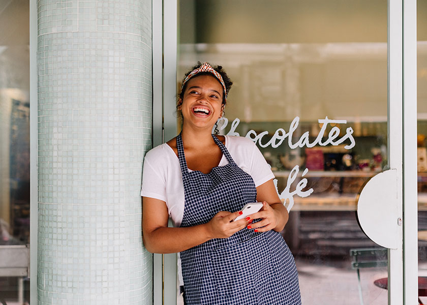 Happy female business owner outside cafe.